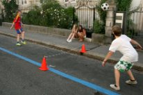 Strassenspiel in einer Begegnungszone: Fussballtennis mit Verkehrshüten.